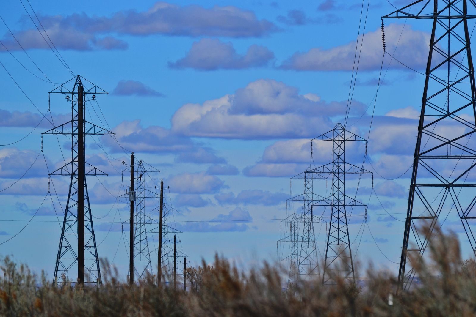 Electricity transmission pylons and power lines under a clear blue summer sky